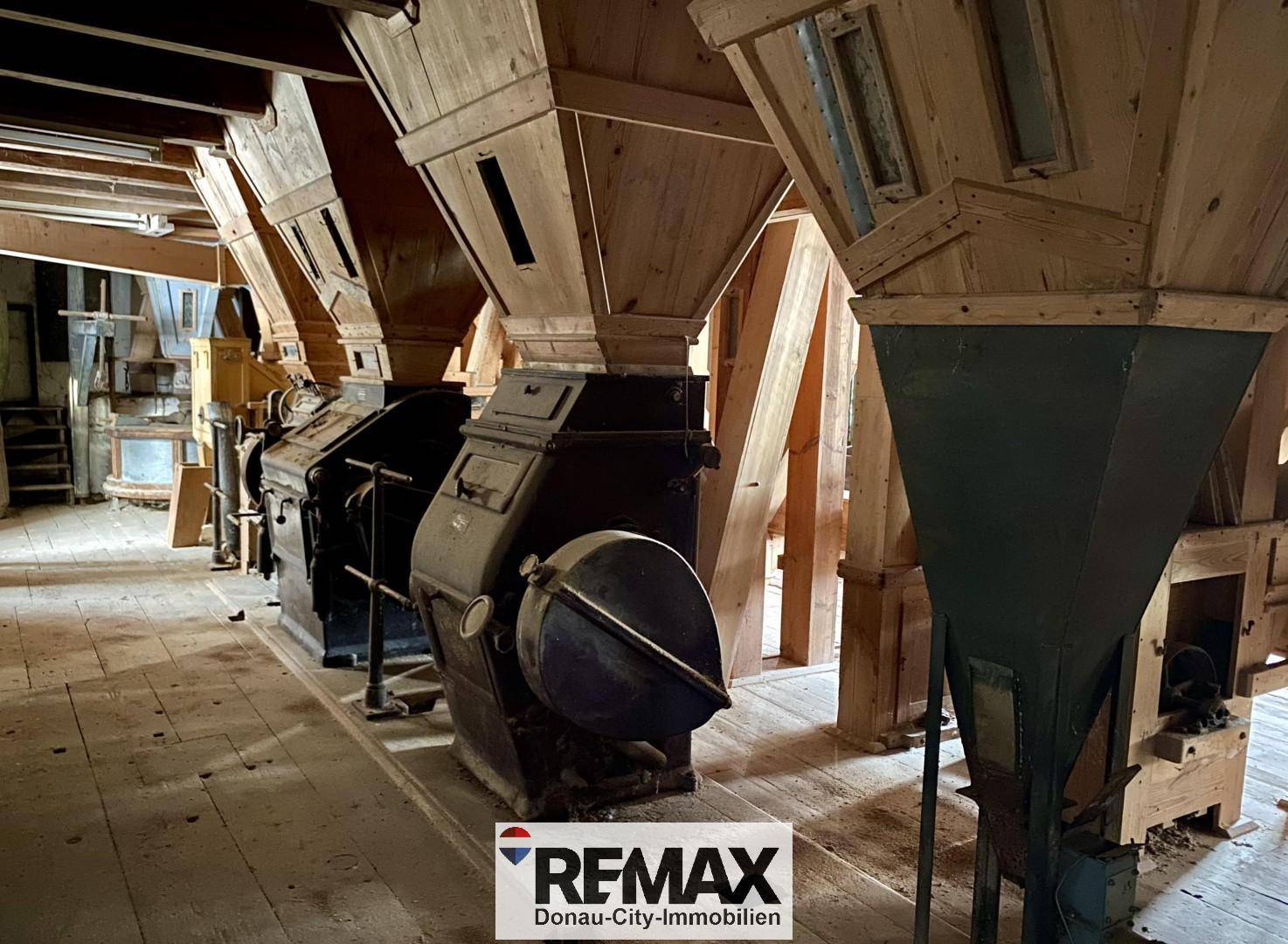 Historische Mühle mit großen Holzkonstruktionen und alten Maschinen, die die Vergangenheit widerspiegeln.
