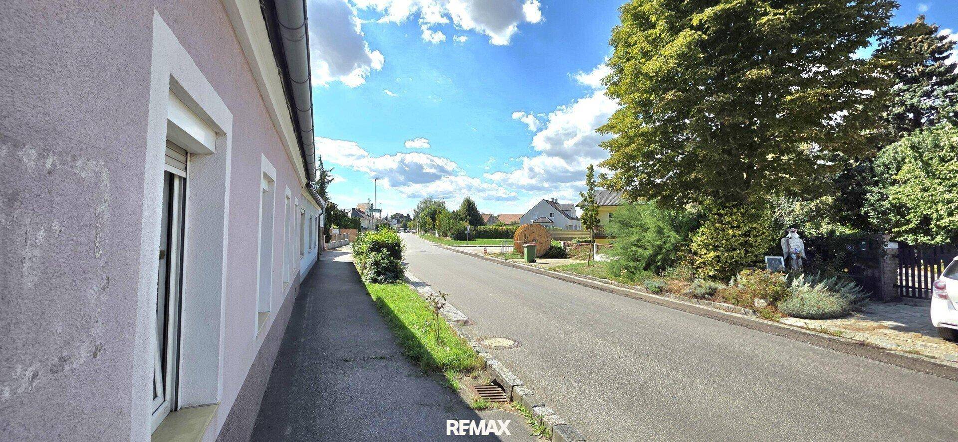Seitenansicht der Immobilie entlang der Straße mit Bürgersteig und Bäumen.