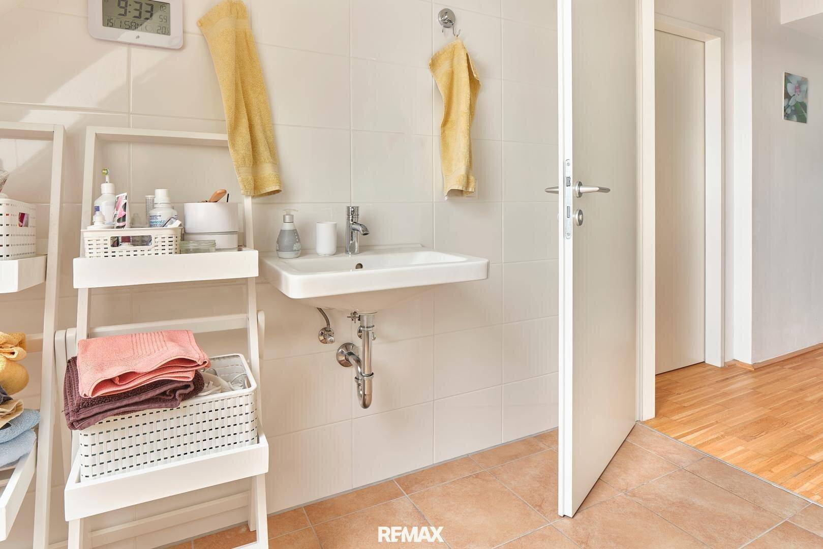 Modernes Badezimmer mit weiß gefliesten Wänden und einem einzelnen Waschbecken.