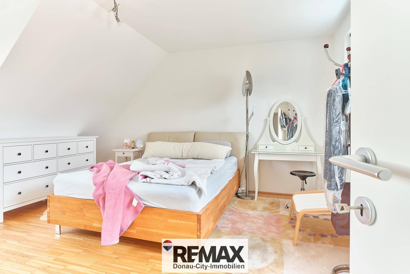 Helles Schlafzimmer im Dachgeschoss mit Holzboden, Bett und Schminktisch.