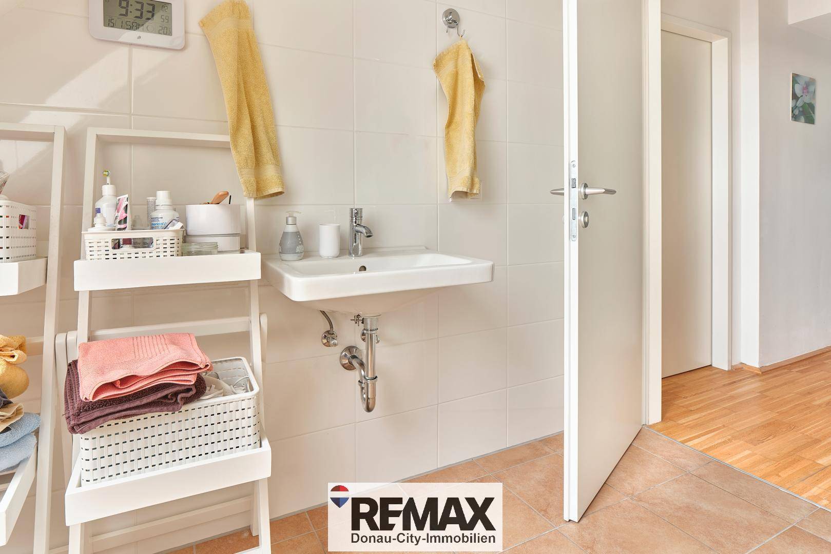 Modernes Badezimmer mit Fliesenboden, Einzelwaschbecken und offenem Regal.