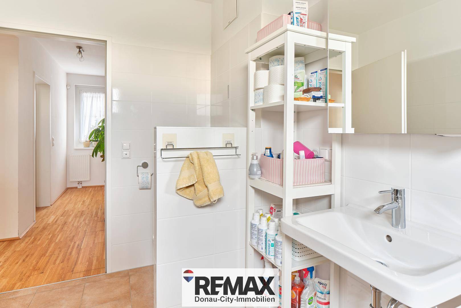 Badezimmer mit Waschbecken, Spiegelschrank und Zugang zum Flur.