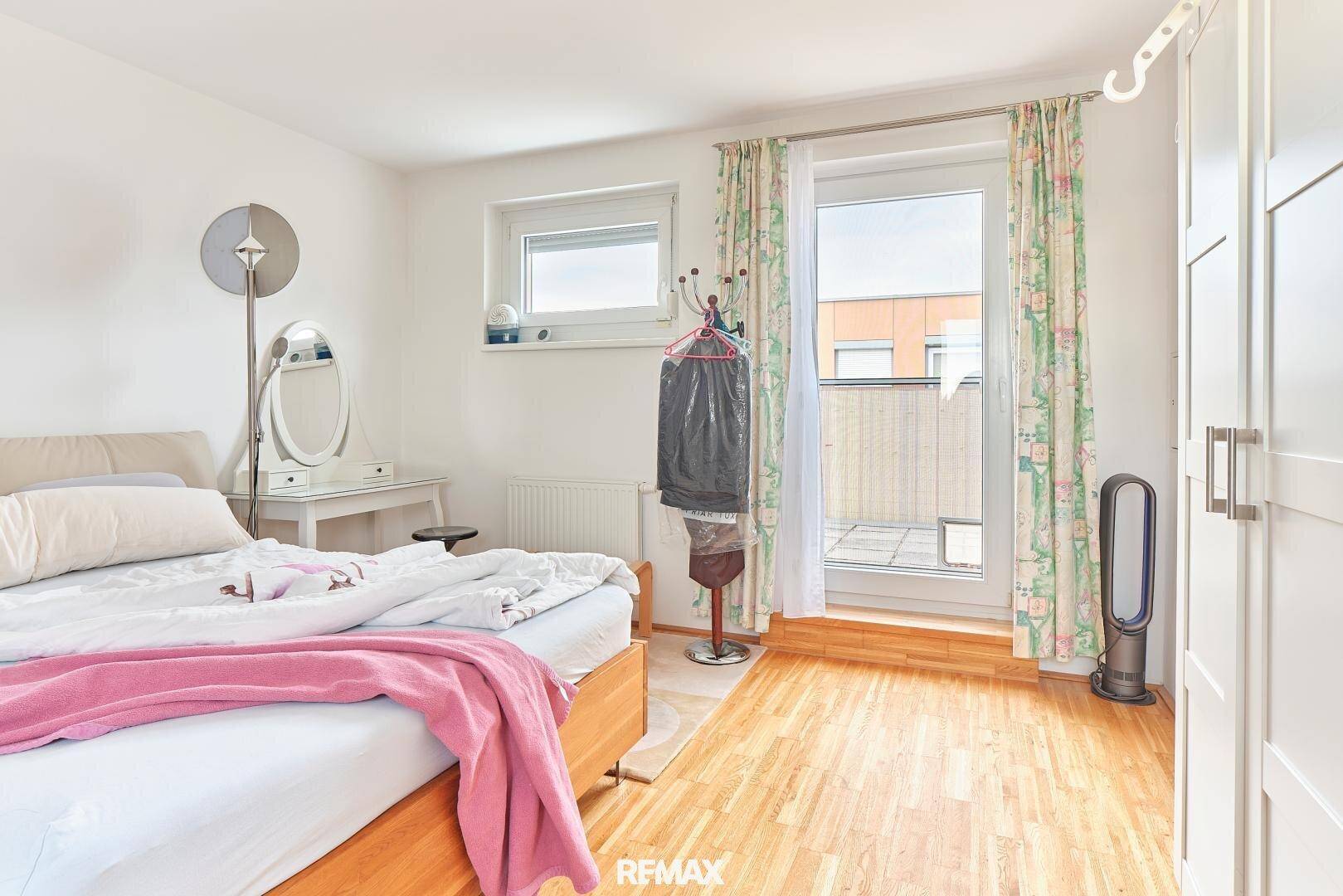 Schlafzimmer mit Holzboden, Bett und Zugang zu einer Dachterrasse.