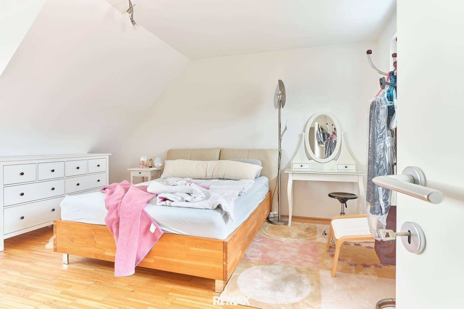 Helles Schlafzimmer mit Holzboden, Dachschräge und einem Schminktisch im Dachgeschoss.