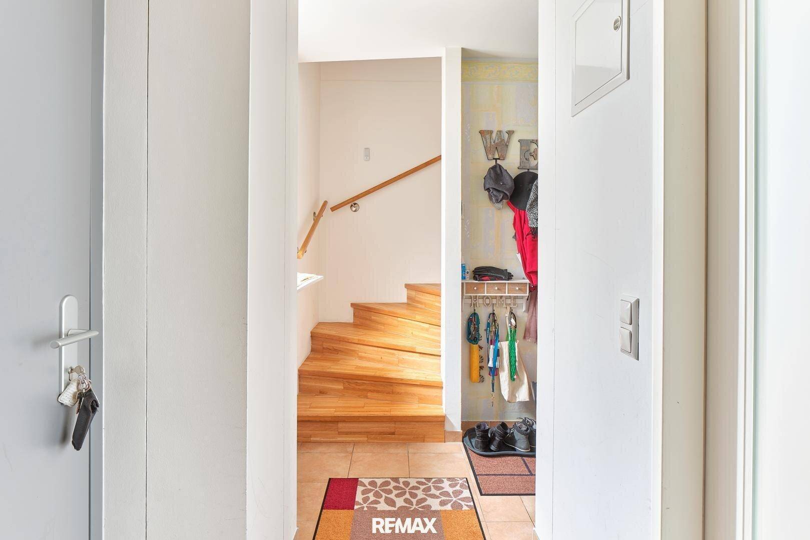 Eingangsbereich mit Garderobe und Holztreppe, die in die oberen Stockwerke führt.