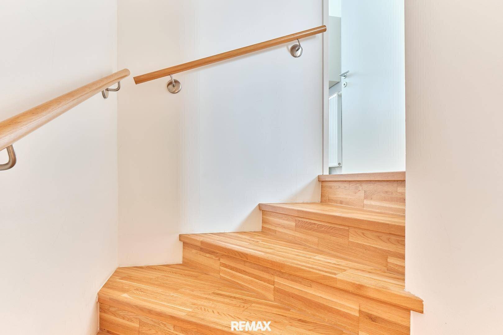 Holztreppe mit Handlauf, die die verschiedenen Etagen des Hauses verbindet.