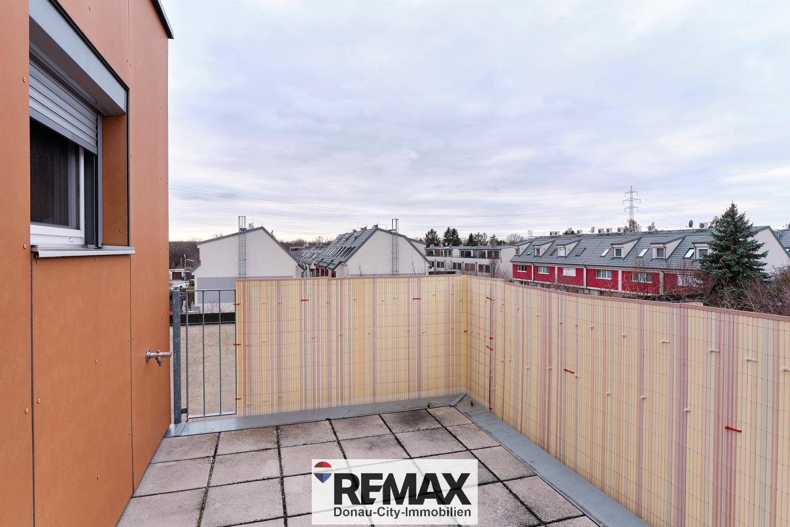 Weitläufige Terrasse mit Blick auf die umliegende Wohnbebauung und den Himmel.