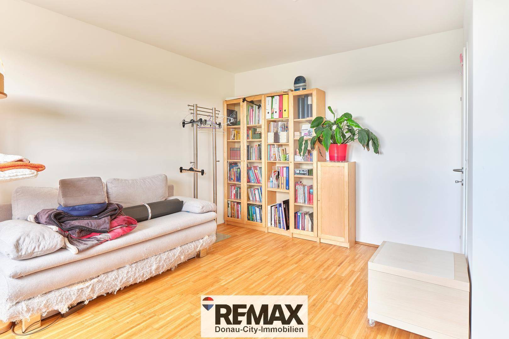 Geräumiges Schlafzimmer mit Holzboden, Bücherregal und Sofa.