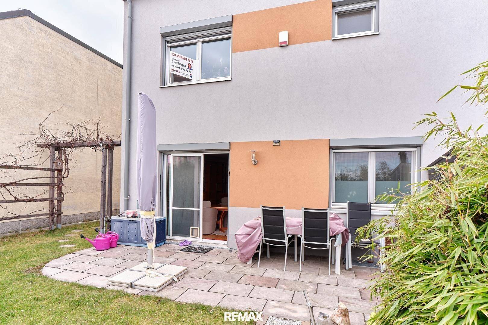 Hinterhof mit gepflasterter Terrasse, Gartenmöbeln und Zugang zum Garten.