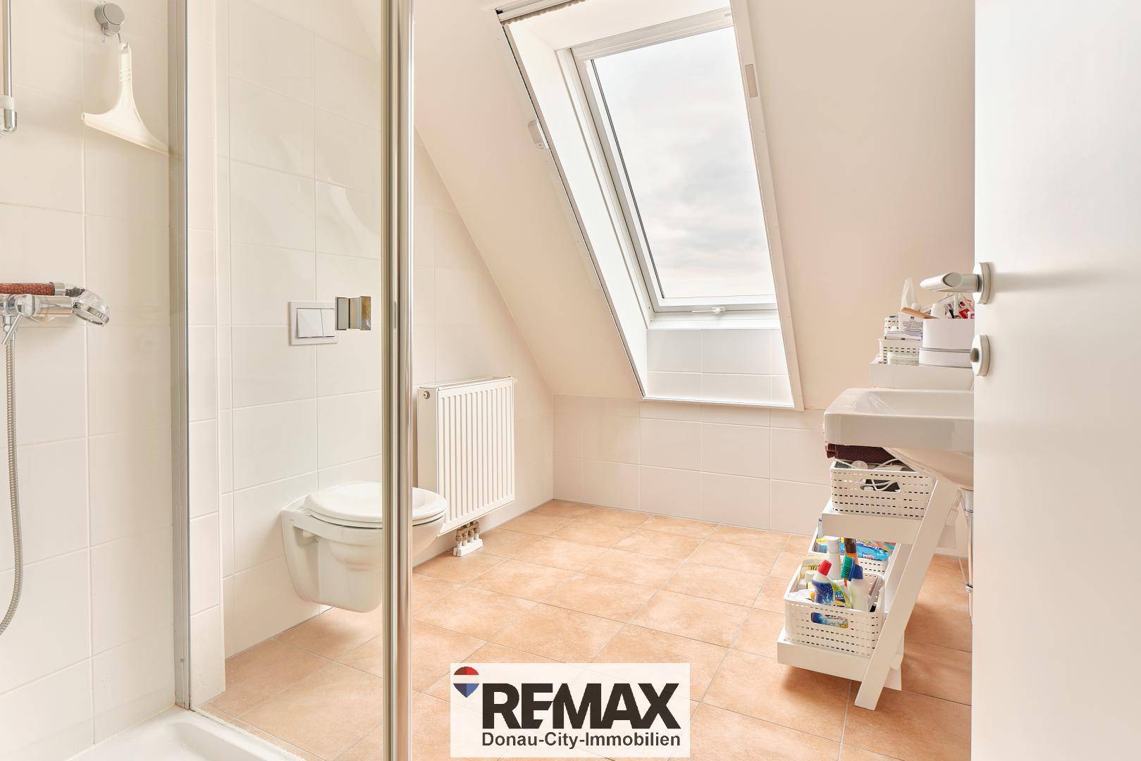 Helles Badezimmer im Dachgeschoss mit Dachfenster, Dusche und Wand-WC.