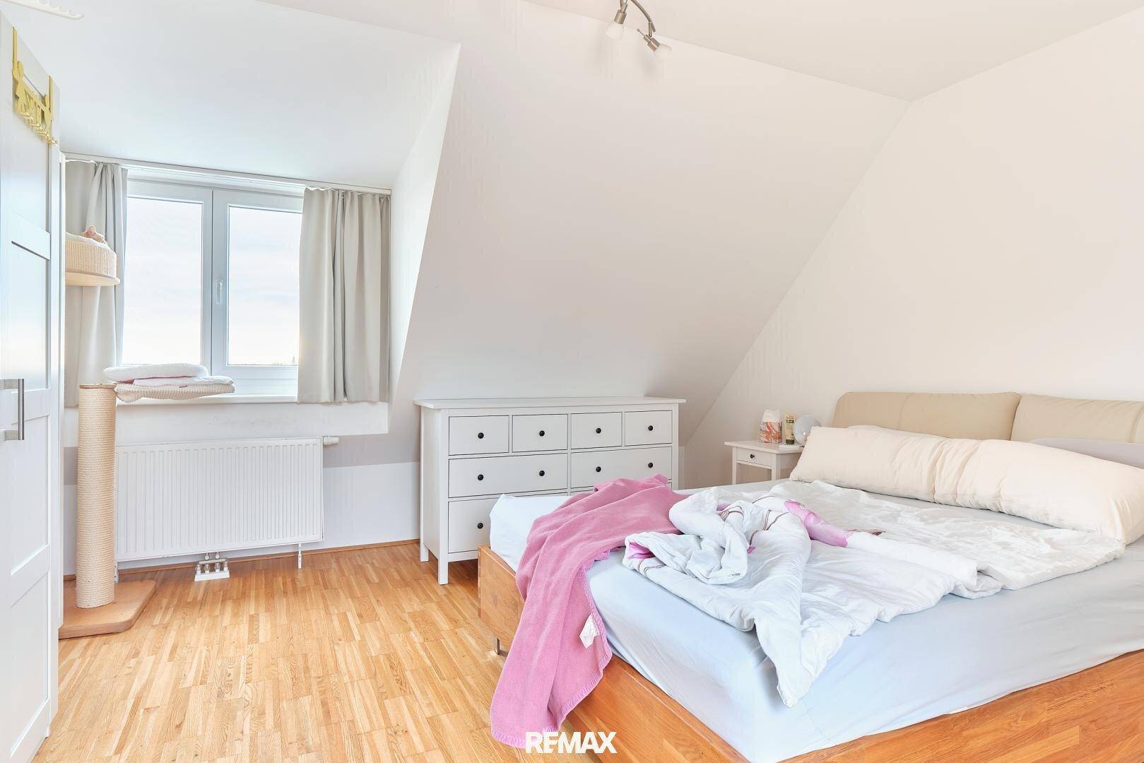Gemütliches Schlafzimmer mit Holzboden, Fenster und Dachschräge im Dachgeschoss.