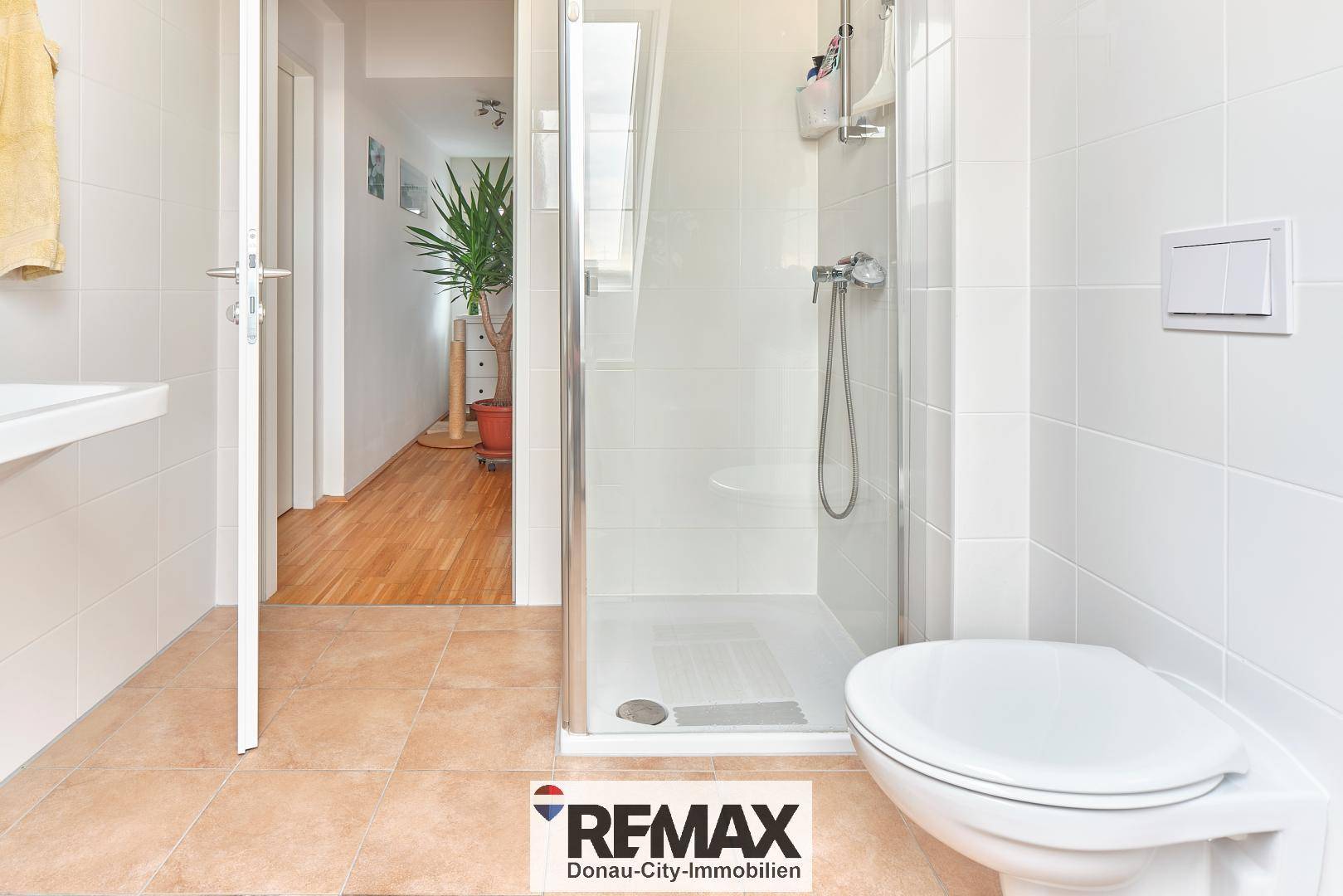 Badezimmer mit Duschkabine, Wand-WC und Zugang zum Flur.
