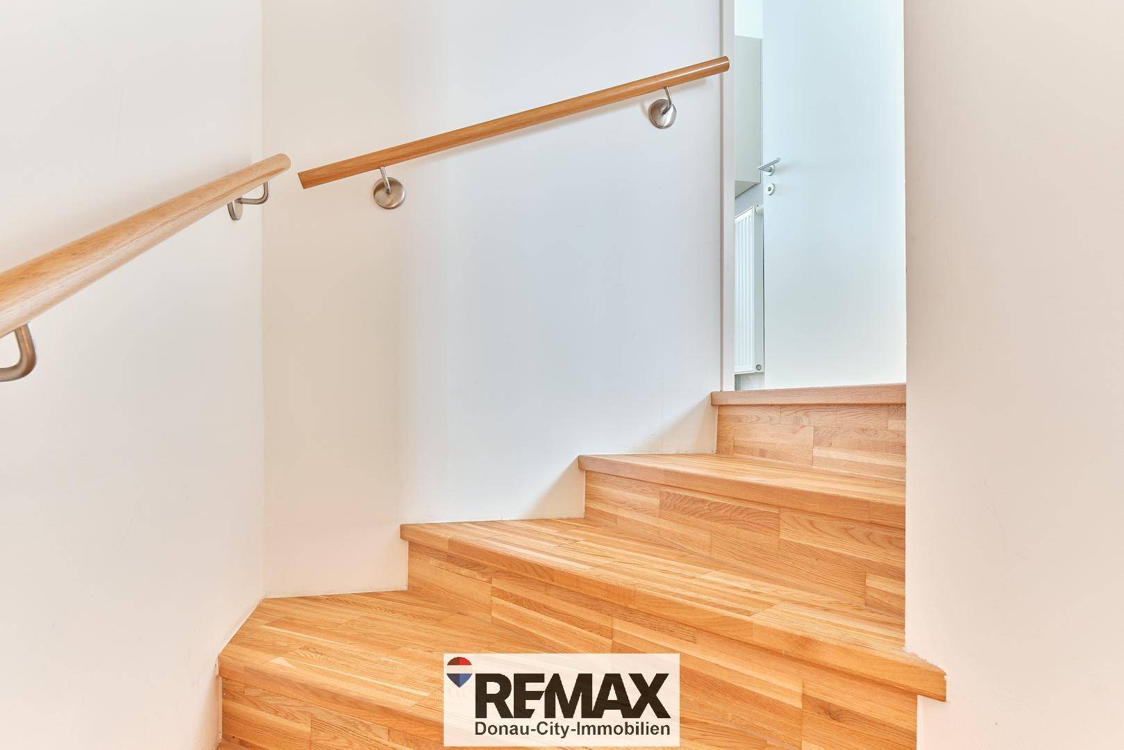 Holztreppe mit Handlauf führt in das obere Stockwerk des Hauses.