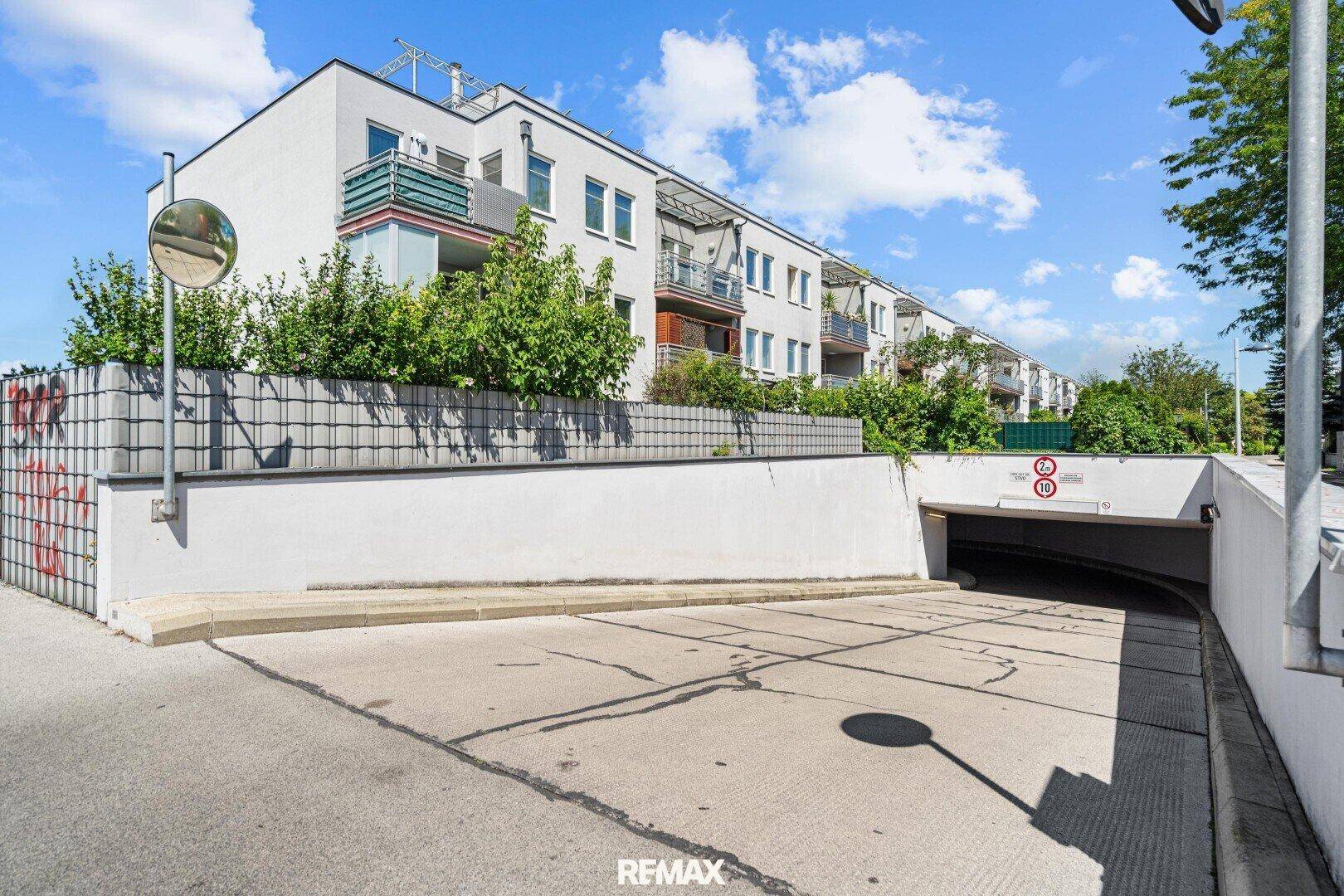 Zufahrt zur Tiefgarage eines modernen Wohnkomplexes mit mehreren Balkonen.