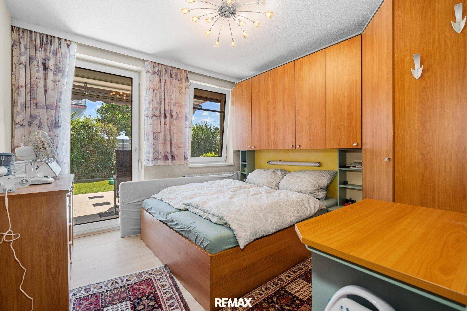 Schlafzimmer mit Holzeinbauschränken, Doppelbett und direktem Zugang zum Gartenbereich.