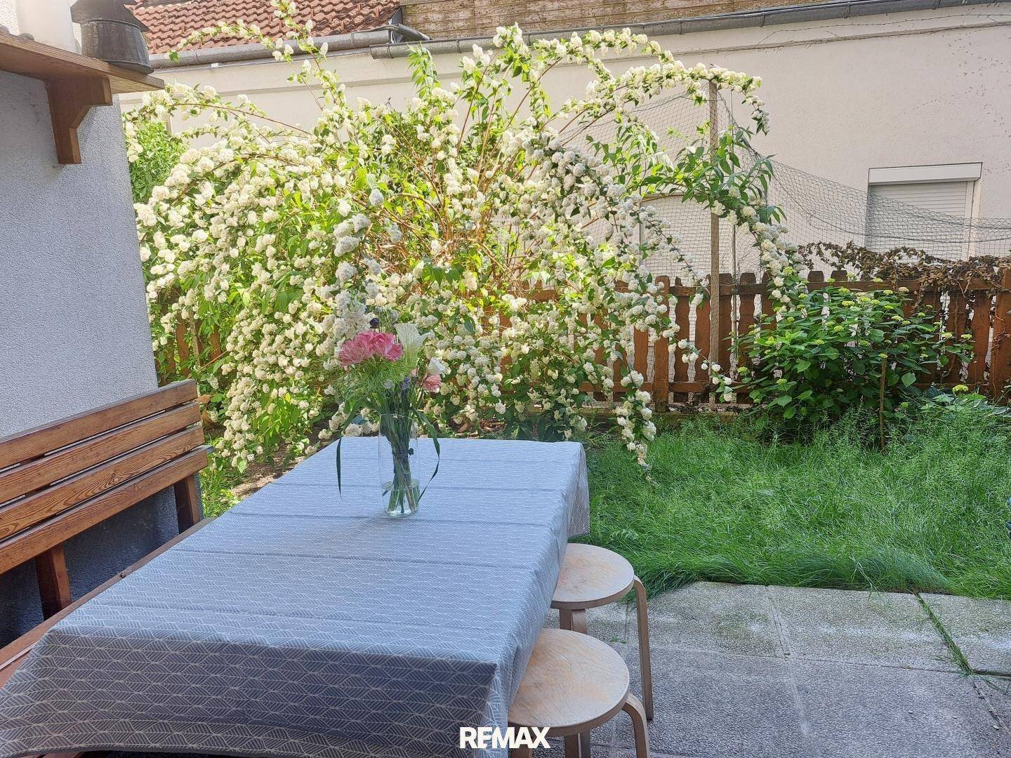 Idyllischer Gartenbereich mit Esstisch und Sitzbank, umgeben von üppig blühenden Sträuchern, perfekt für Mahlzeiten im Freien.