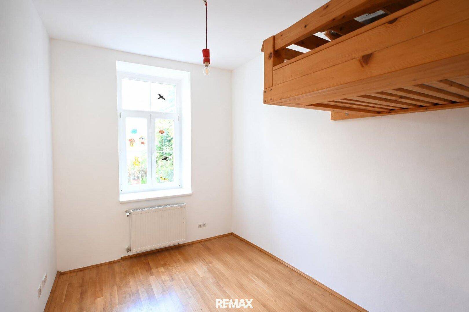 Helles Schlafzimmer mit Holzboden und weiß gestrichenen Wänden, ausgestattet mit einem Hochbett aus Holz.