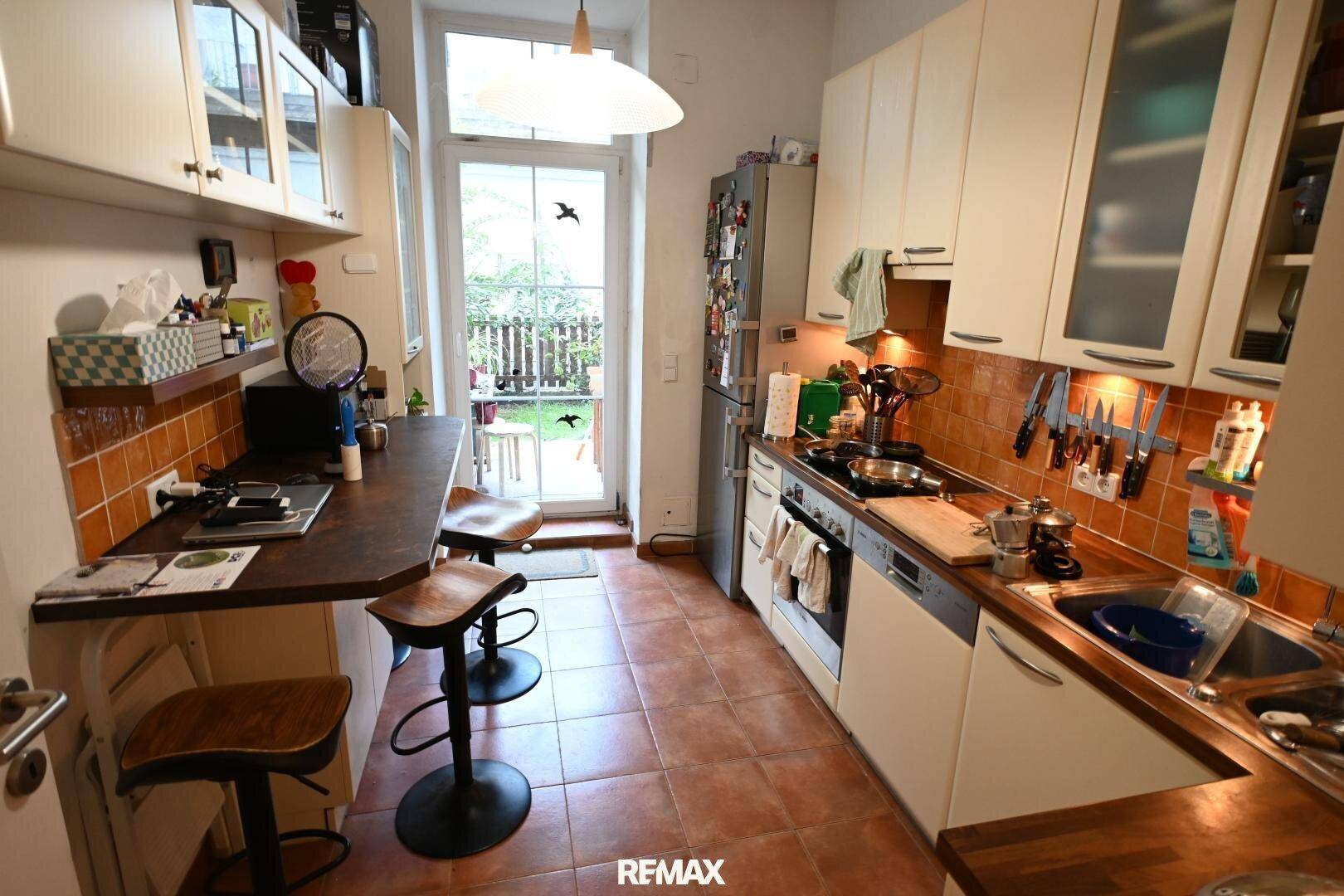 Küche mit Frühstücksbar und direktem Zugang zum Garten, bietet eine helle und praktische Kochumgebung.
