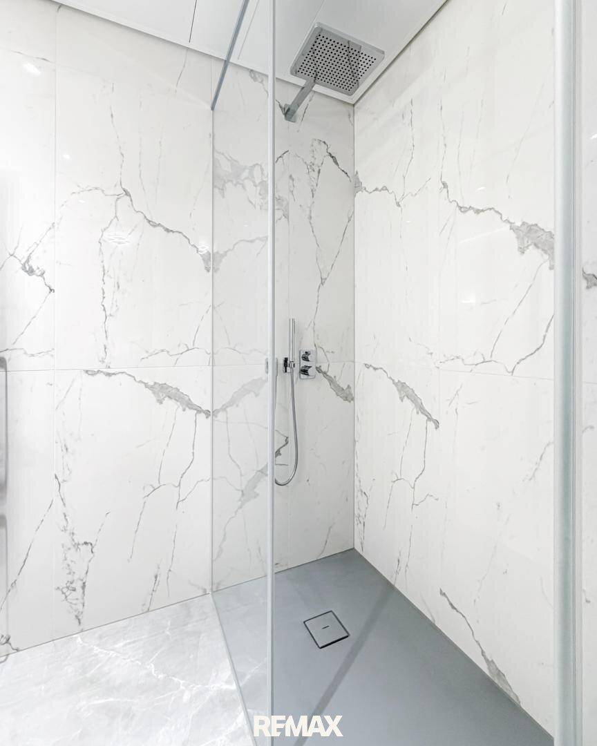 Elegante Duschkabine mit Marmoroptik-Fliesen und moderner Regendusche.