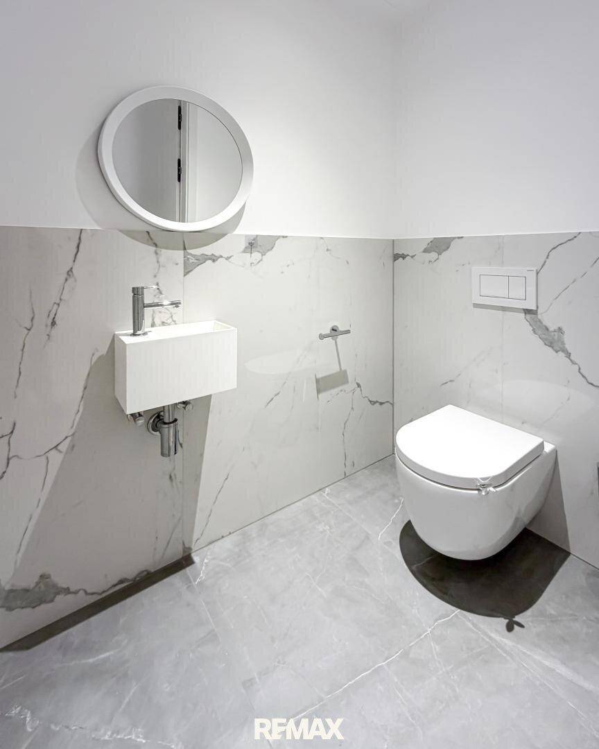 Modernes Gäste-WC mit wandhängender Toilette und stilvollen Marmorfliesen.