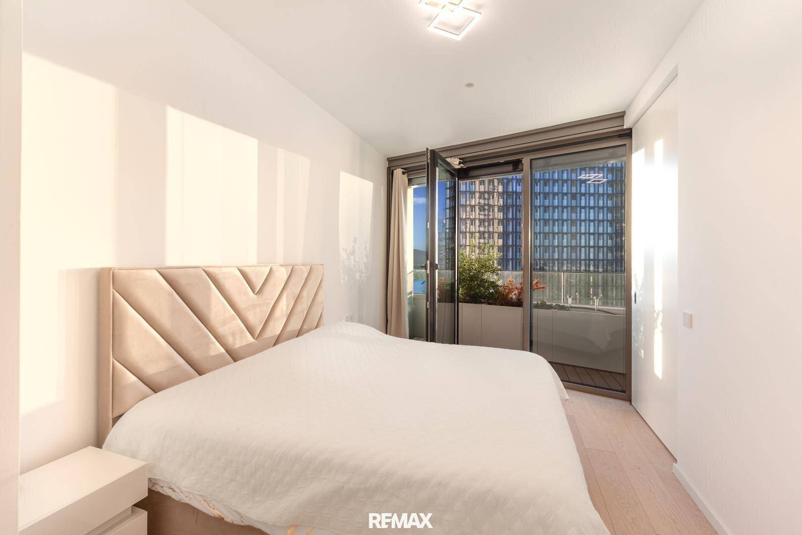 Helles Schlafzimmer mit modernem Bett und direktem Zugang zu einem privaten Balkon.