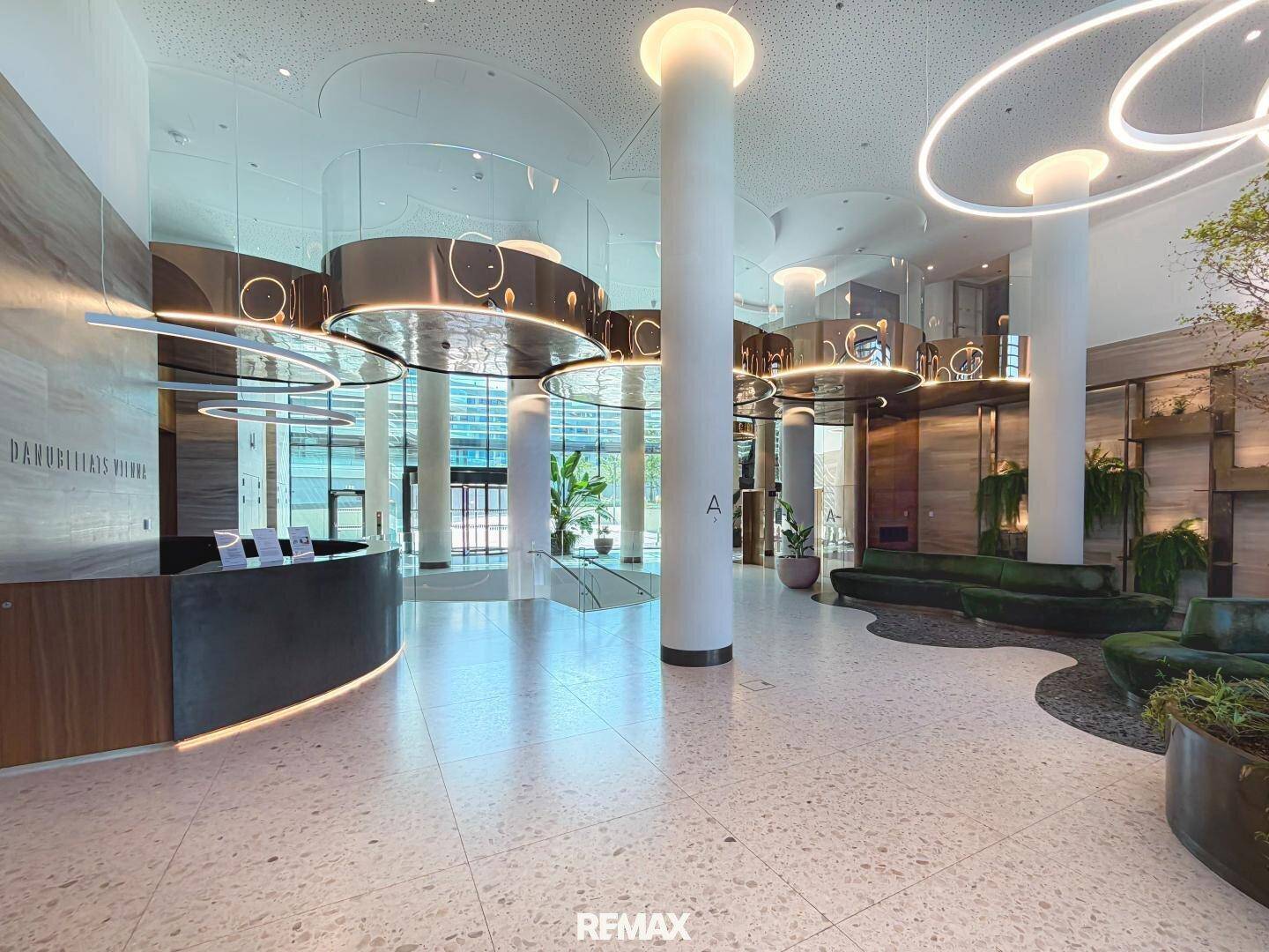 Elegante und moderne Lobby mit hohen Decken, stilvoller Beleuchtung und Rezeption.