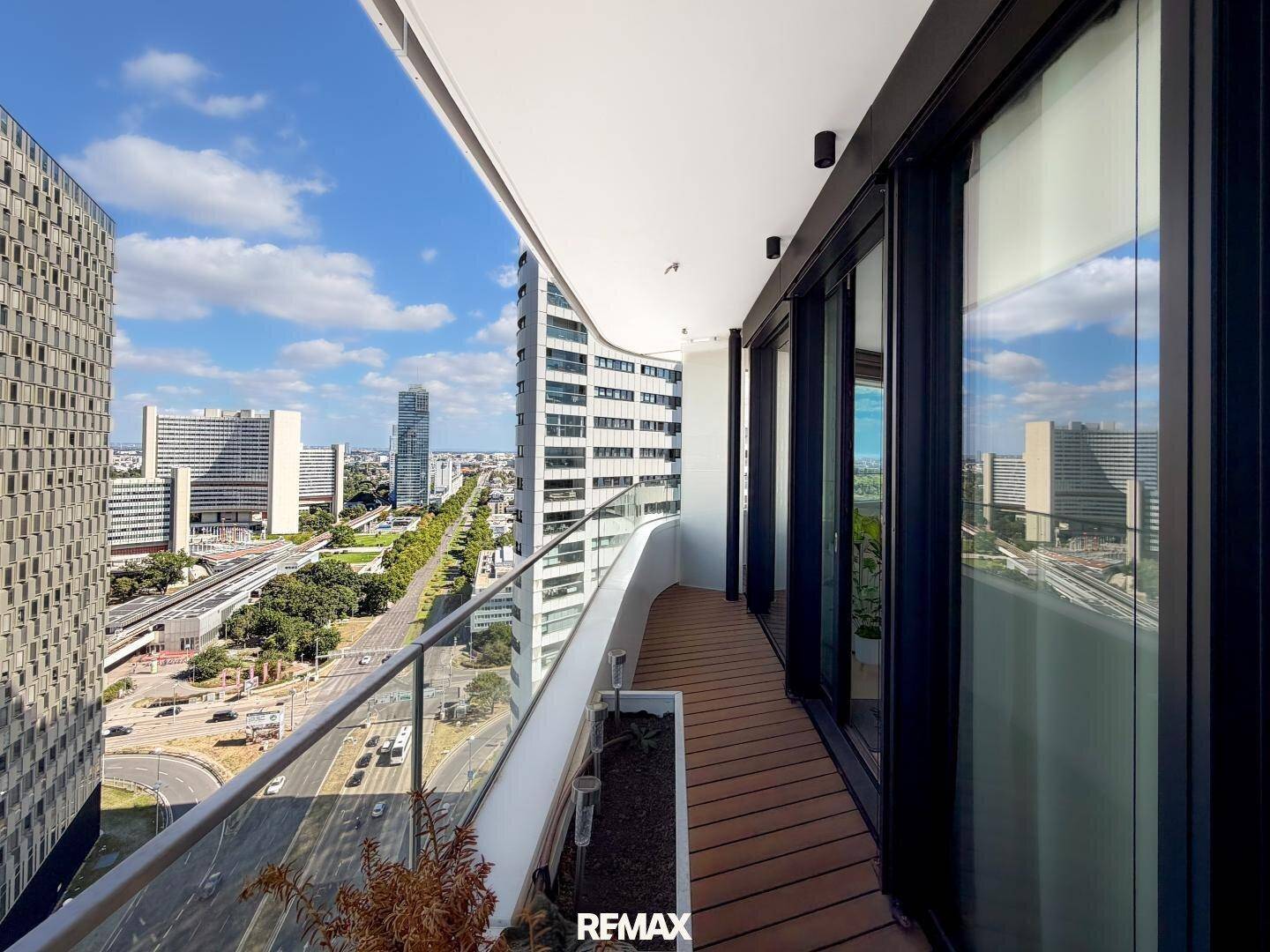 Breiter Balkon mit Holzdeck und weitem Blick auf die umliegende Stadtlandschaft.