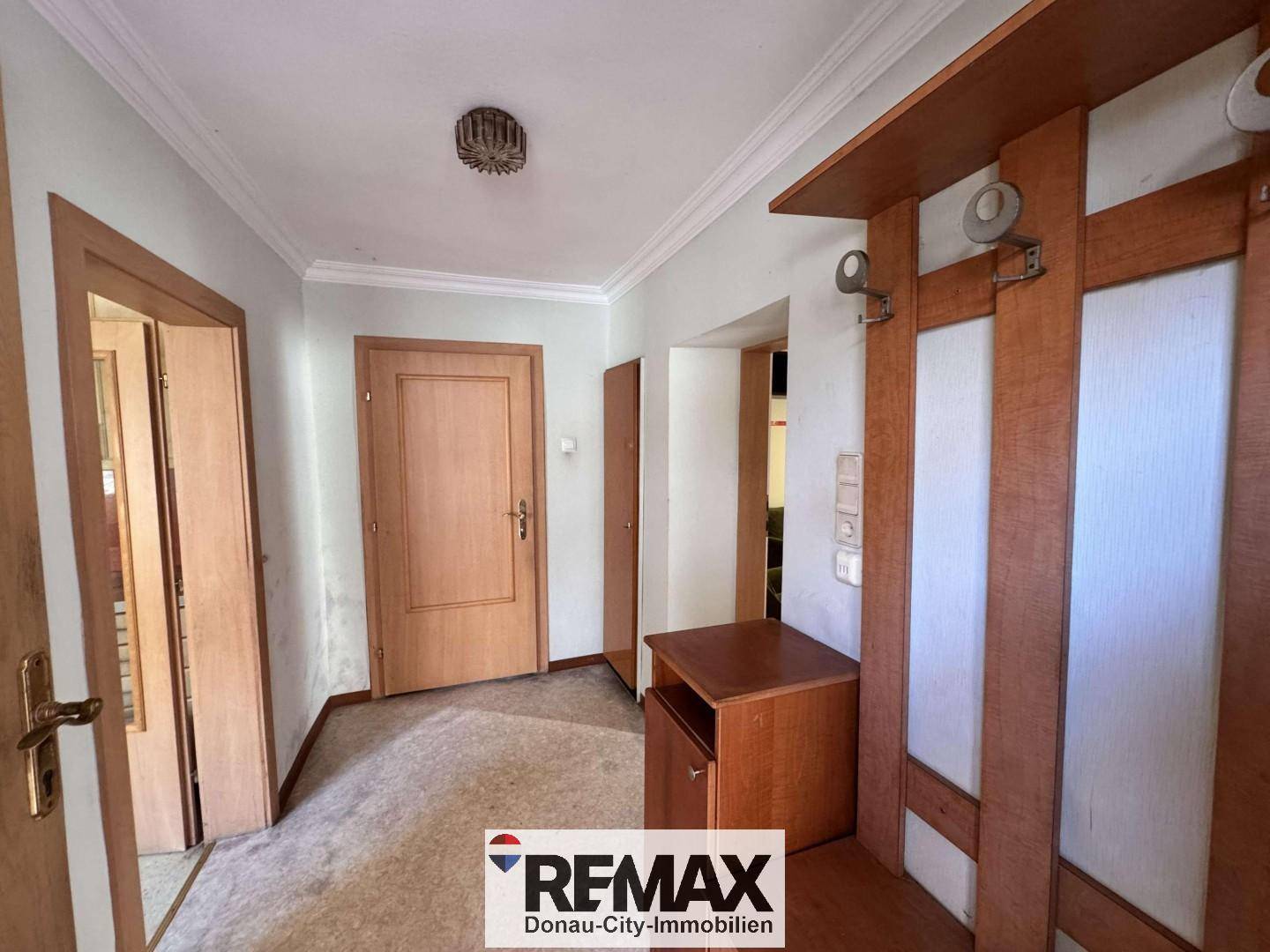 Heller Flur mit Garderobe, Holztüren und Teppichboden.
