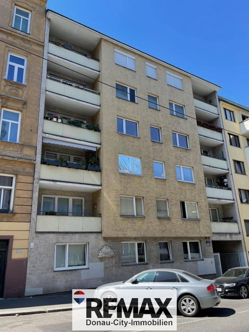 Mehrstöckiges Wohngebäude mit Balkonen und gelber Fassade an einer städtischen Straße.