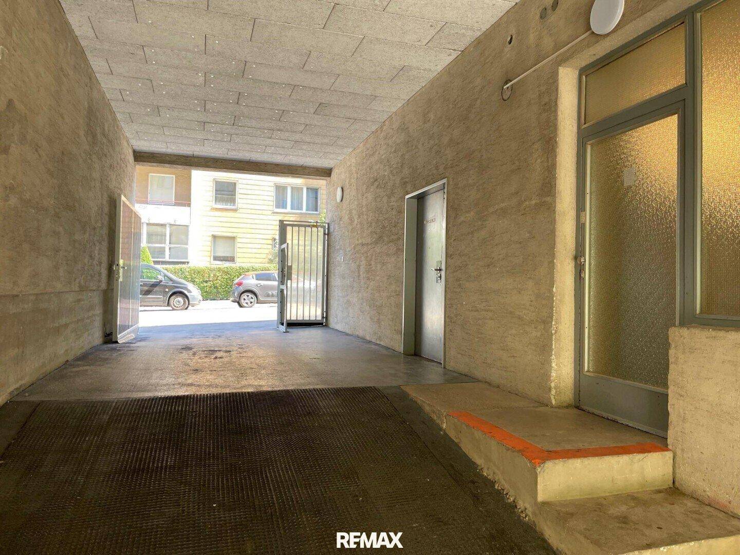 Überdachter Eingangsbereich mit Rampe, der zu einem Innenhof oder einer Garage führt.
