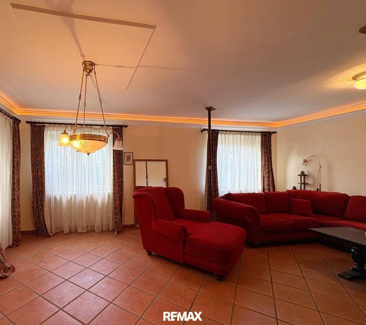 Gemütliches Wohnzimmer mit roten Sofas, Terrakotta-Fliesen und indirekter Beleuchtung.