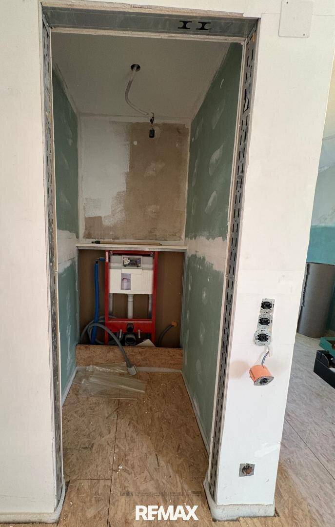 Rohbau eines Badezimmers oder WCs mit installierter Toilettenspülung und OSB-Boden.