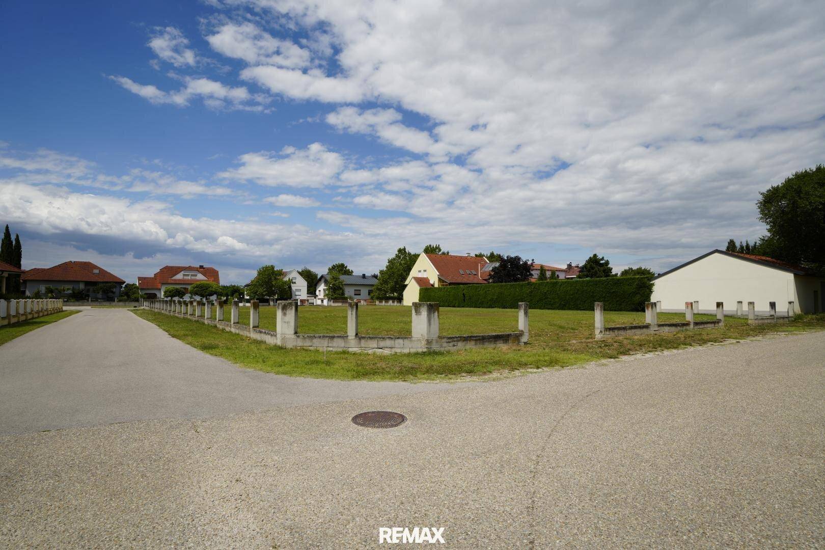 Panoramablick von der Straße auf das weitläufige Grundstück mit angrenzenden Gebäuden und viel Grün.