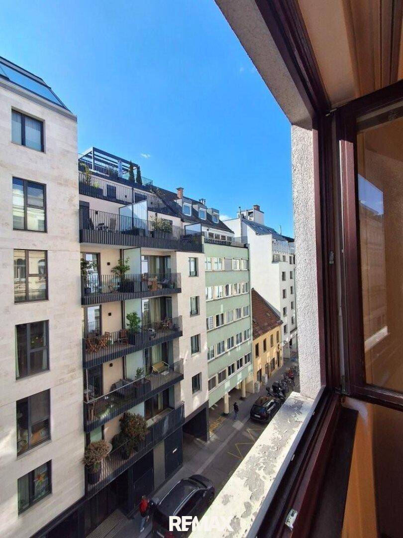 Blick aus dem Fenster auf eine belebte Stadtstraße mit modernen und traditionellen Gebäuden.