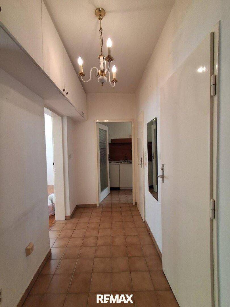 Heller Flur mit Fliesenboden, Spiegelschrank und Blick in die Küche.