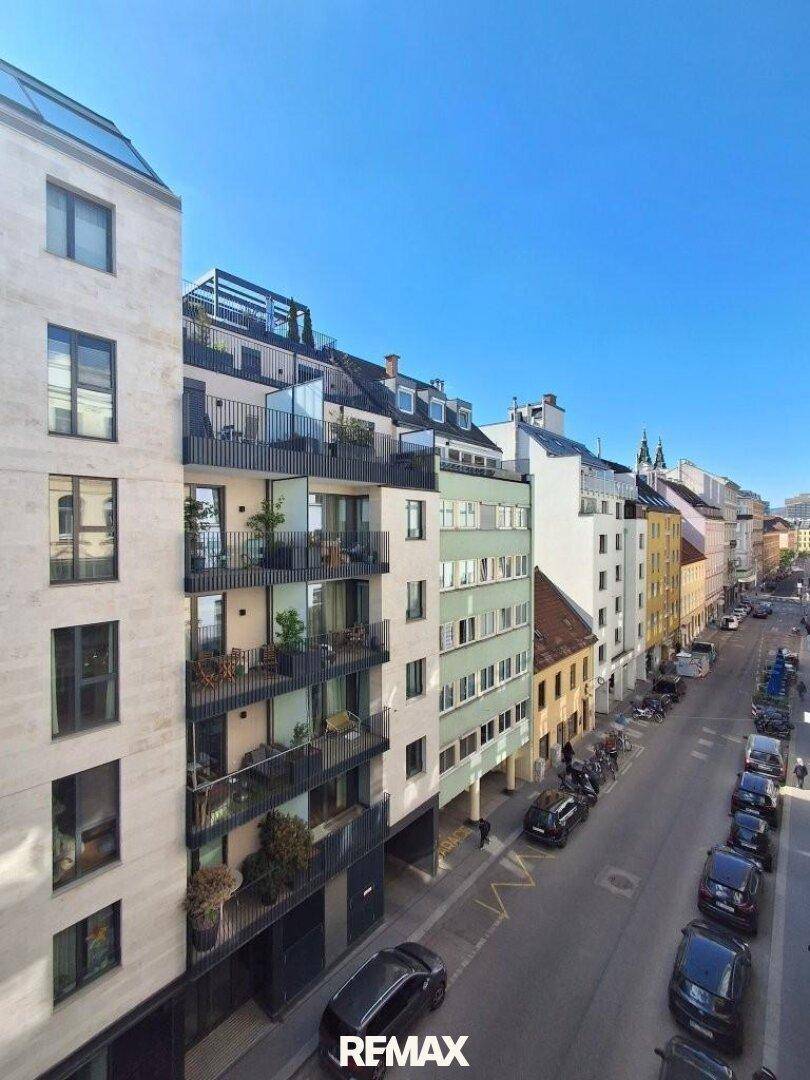 Blick aus dem Fenster auf eine belebte Stadtstraße mit modernen und traditionellen Gebäuden.
