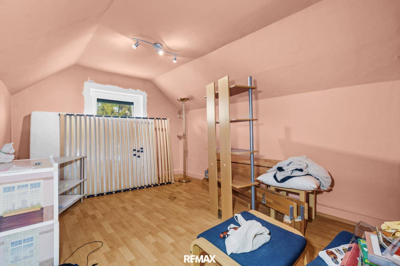 Dachzimmer mit schrägen Wänden, rosa Anstrich und hellem Parkettboden, ideal als Kinderzimmer.