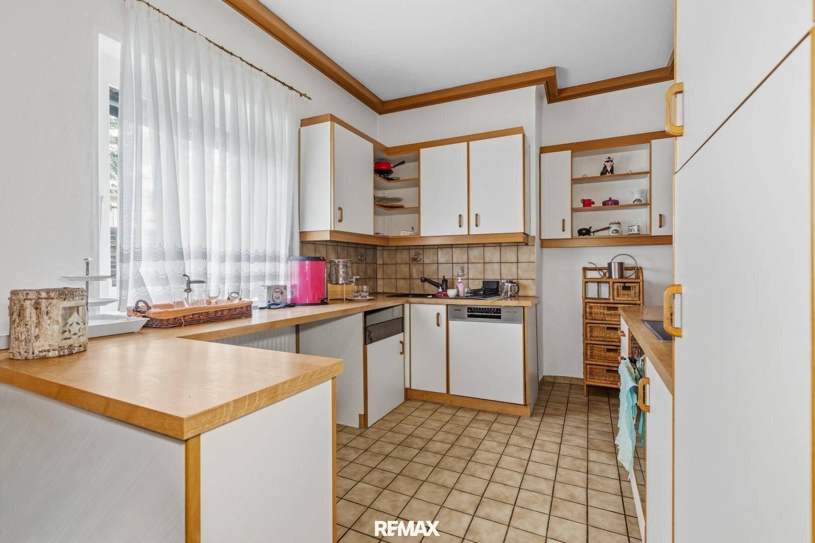 Funktionale Küche mit weißen Schränken, Holz-Arbeitsplatten und gefliestem Spritzschutz.