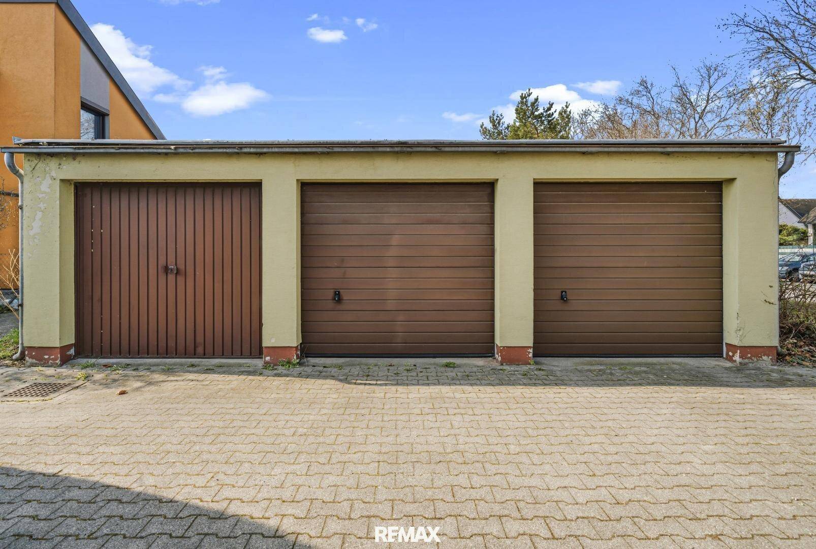 Dreifachgarage mit braunen Toren und gepflasterter Zufahrt.
