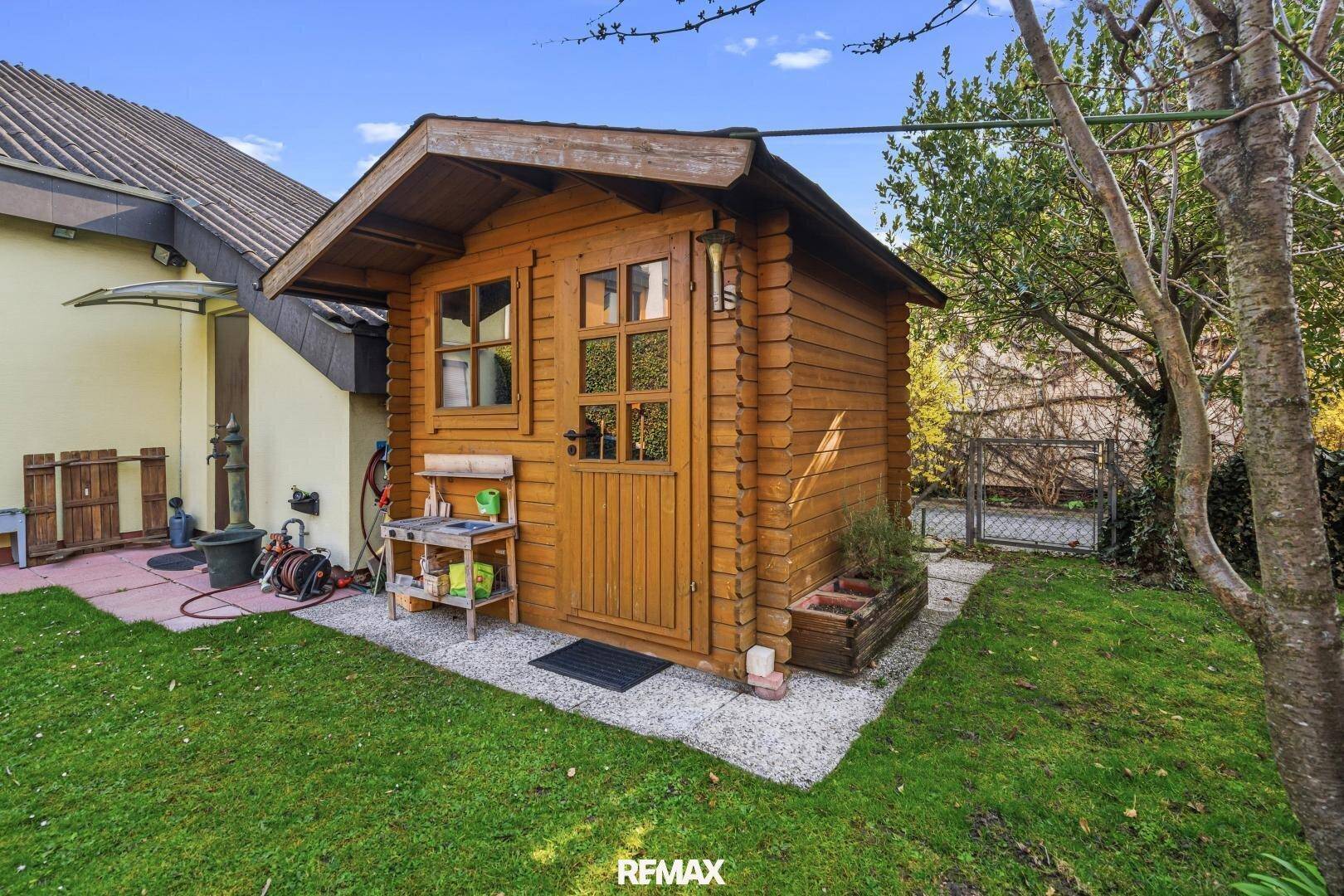 Charmantes Gartenhaus aus Holz im Grünen, ideal für Gartengeräte oder als Rückzugsort.