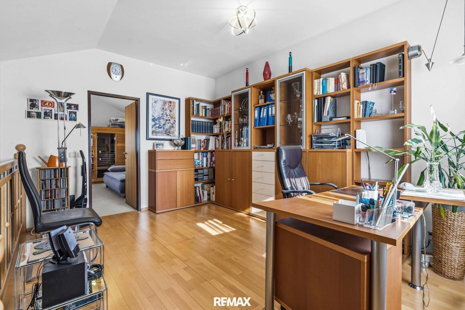 Helles Arbeitszimmer mit umfangreichen Bücherregalen, Schreibtisch und Holzboden.