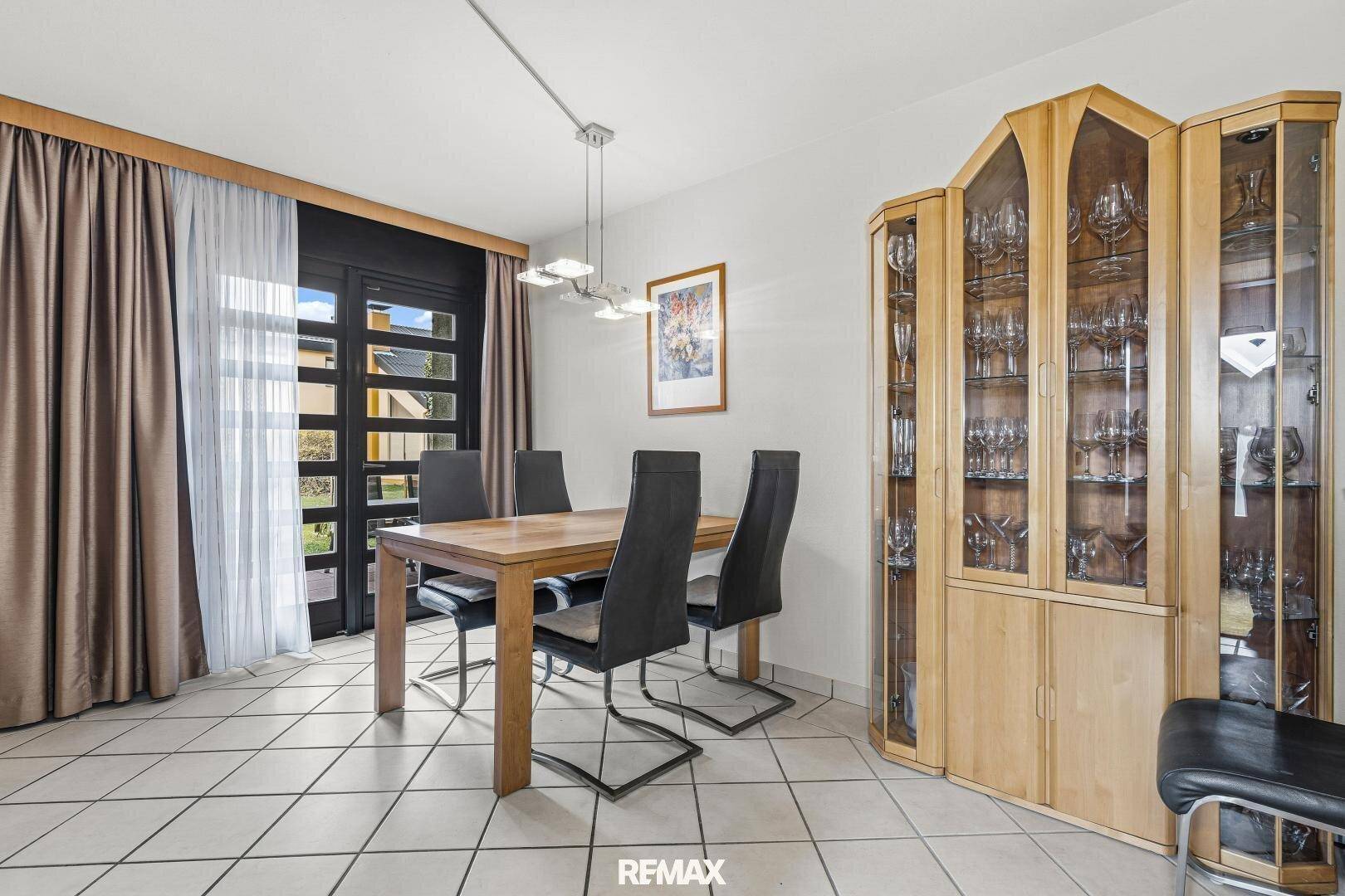 Esszimmer mit Holztisch, schwarzen Stühlen und Zugang zur Terrasse durch eine Glastür.