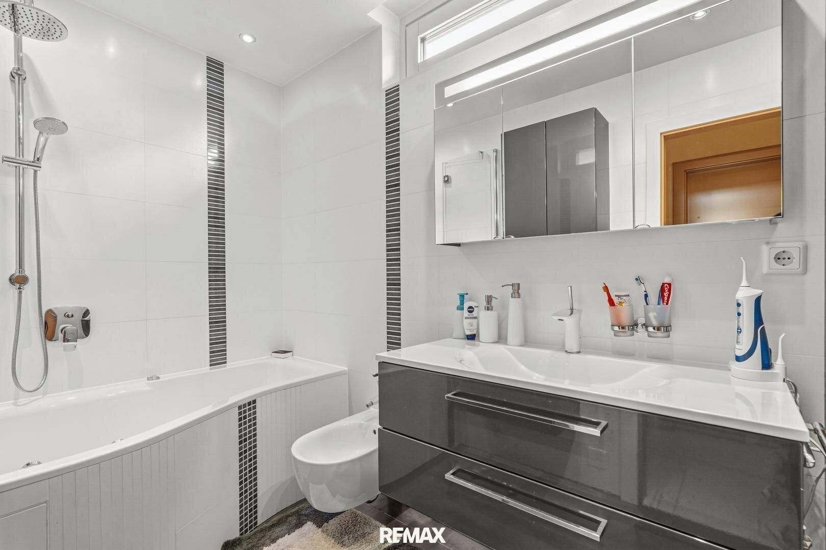 Modernes Badezimmer mit Badewanne, Bidet, Doppelwaschbecken und eleganten Fliesen.