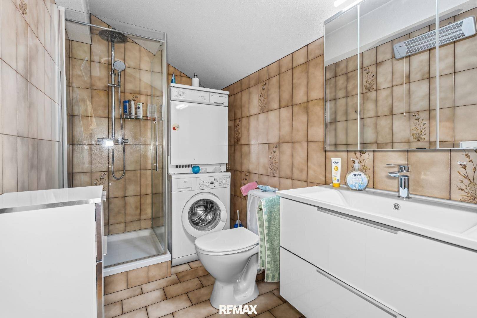 Badezimmer mit Duschkabine, WC, Waschbecken und Waschmaschine/Trockner.