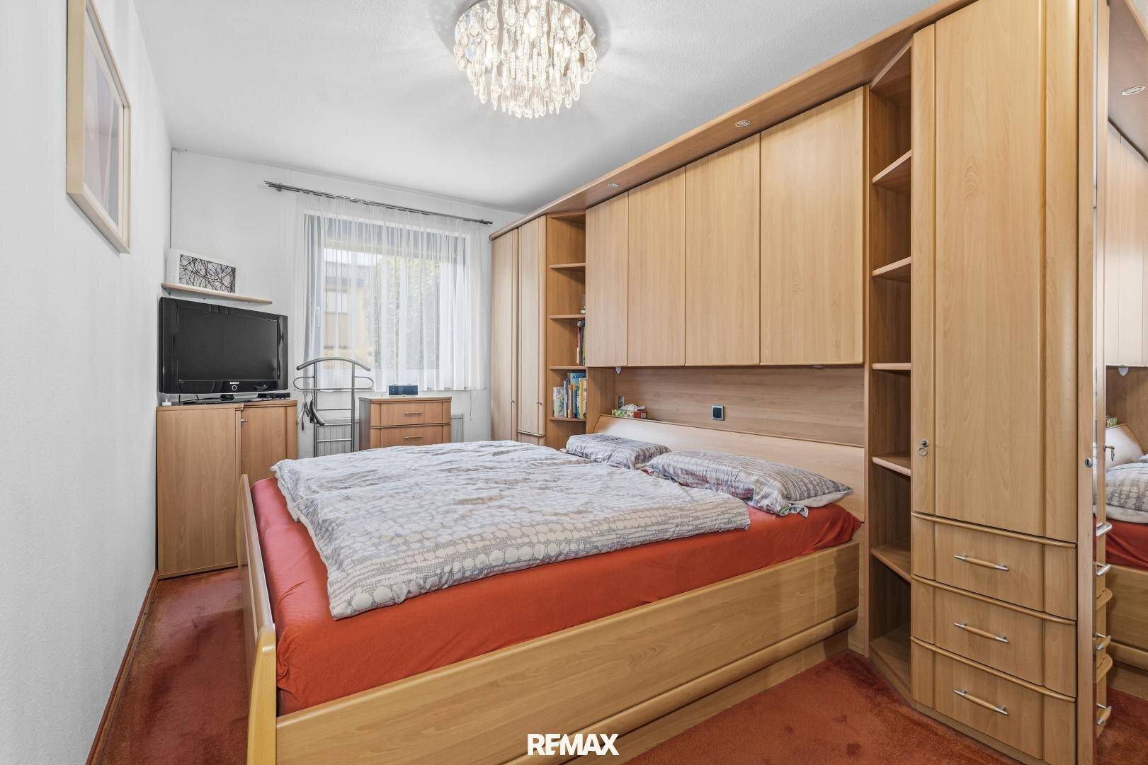 Schlafzimmer mit großem Bett, Einbauschränken aus Holz und Teppichboden.