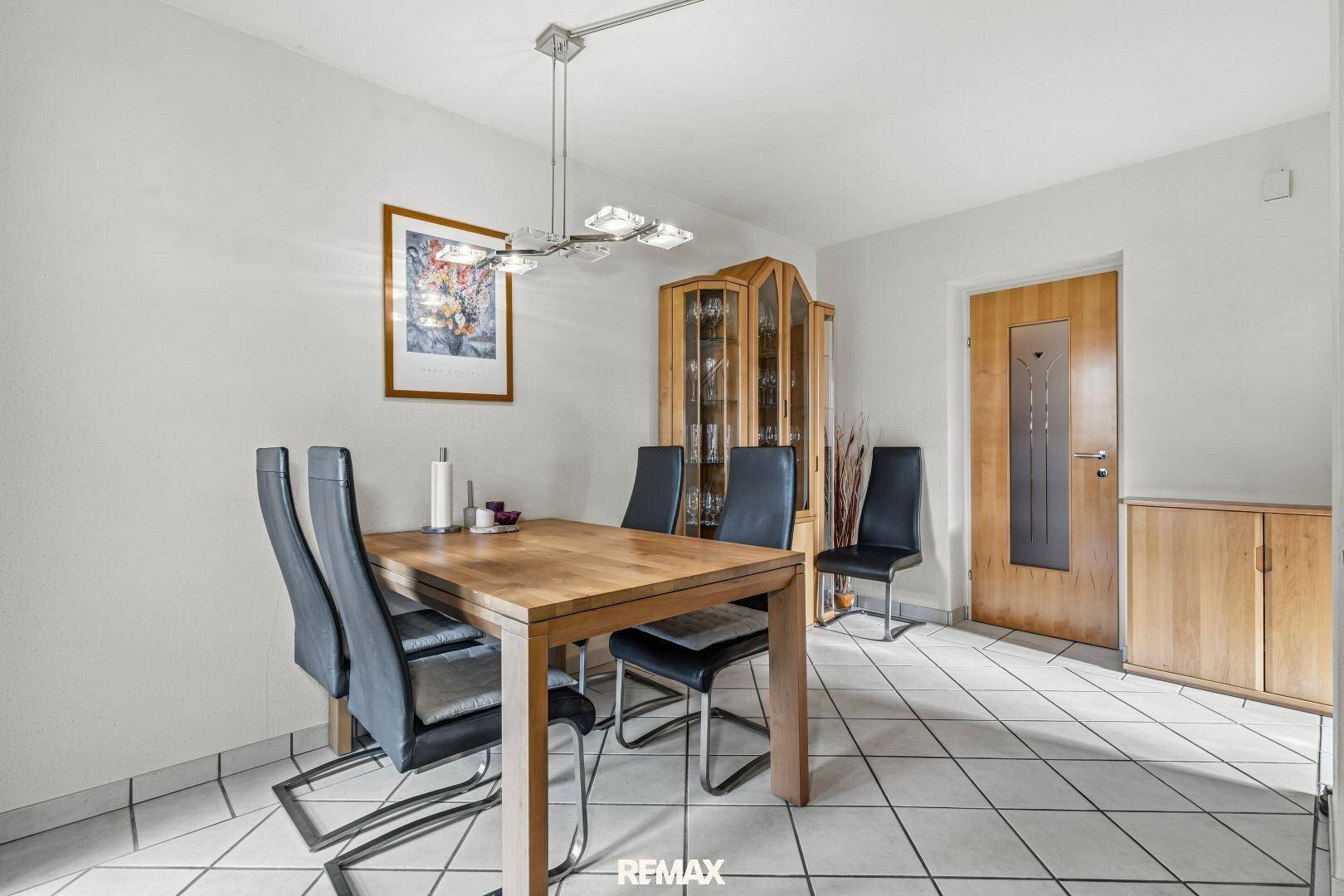 Heller Essbereich mit Holztisch, modernen Stühlen und Fliesenboden.