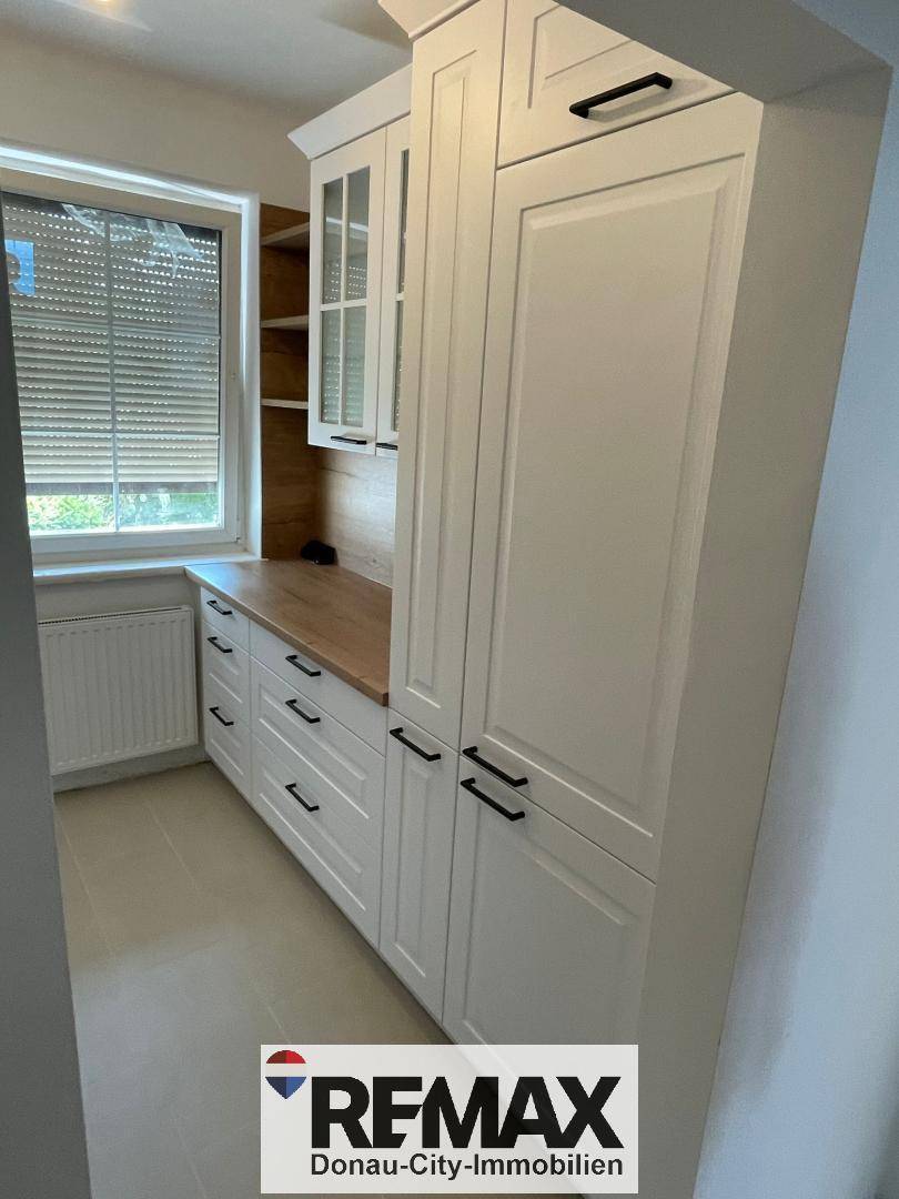 Moderne Küchenschränke in Weiß mit Holzdetails und viel Stauraum.
