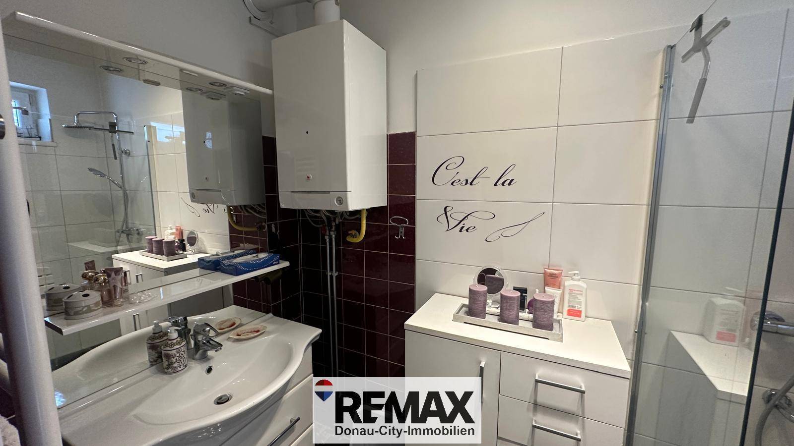 Badezimmer mit Waschbecken, großem Spiegel und Gastherme an der Wand.