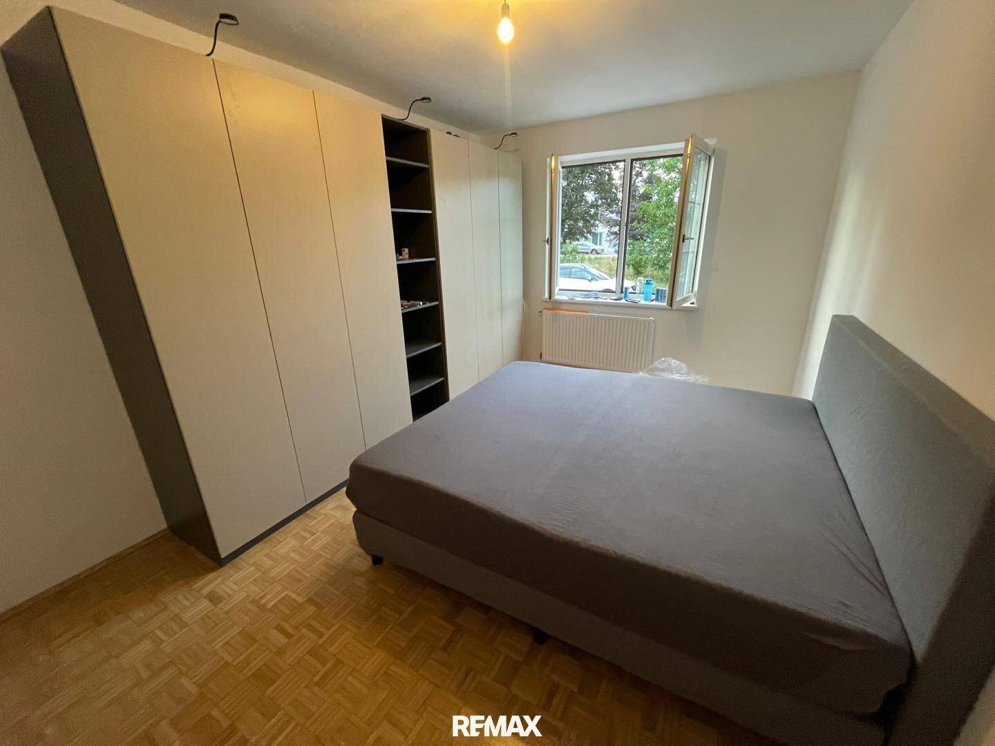 Helles Schlafzimmer mit modernem Bett, Einbauschränken und Parkettboden.