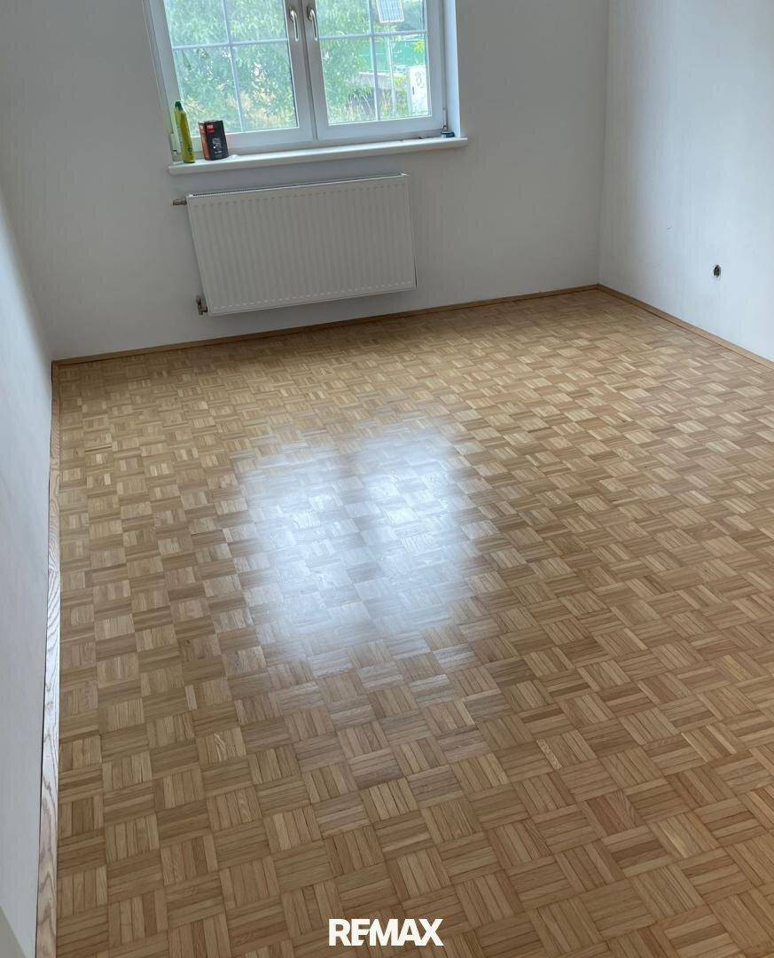 Leerer Raum mit Parkettboden und hellen Wänden, bereit zur individuellen Gestaltung.